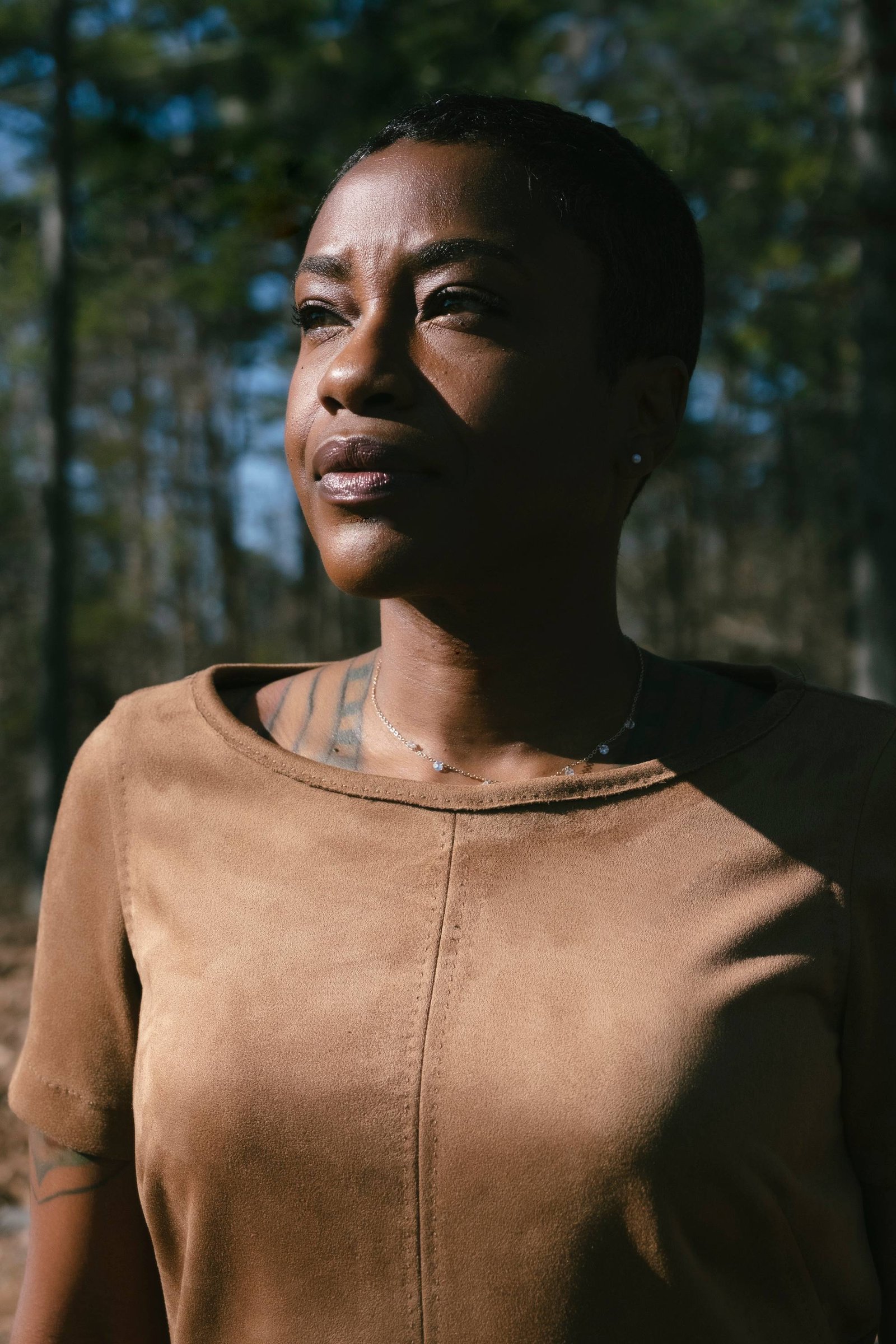 Akilah S. Richards outdoors among trees, looking into the distance